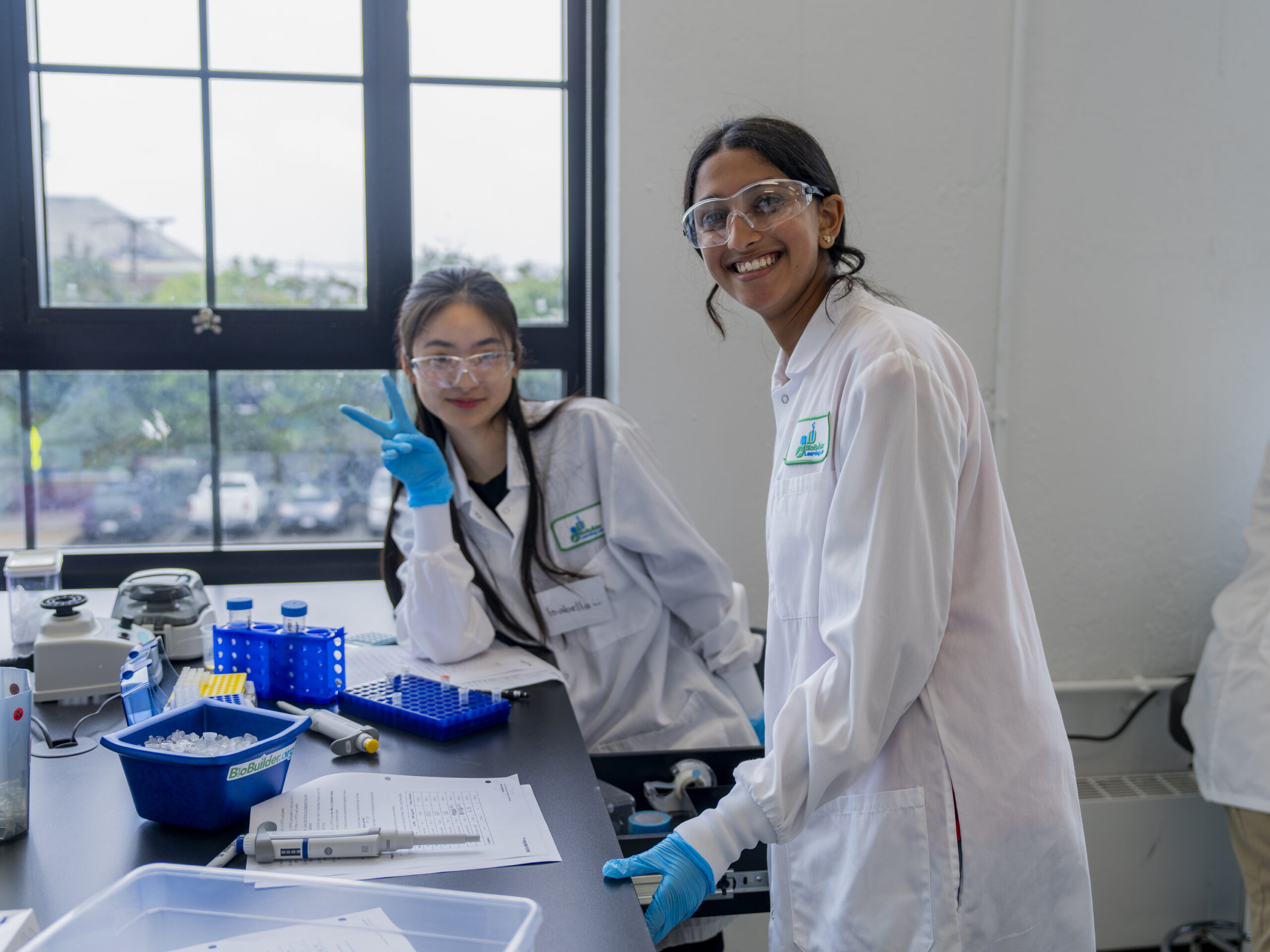 Two people smiling in lab coats