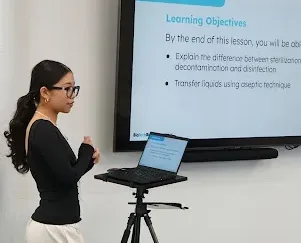 A person in a BioBuilder lab coat mentoring students